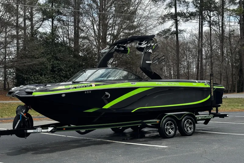Slide: The Image of 2015 Centurion Enzo FS44 boat with green accents on a trailer in a parking lot. - 15