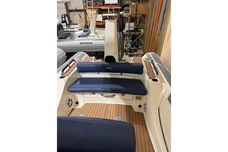 Slide: The Image of 2023 Brig Eagle 8 boat interior with blue seating and wood accents in a showroom. - 5