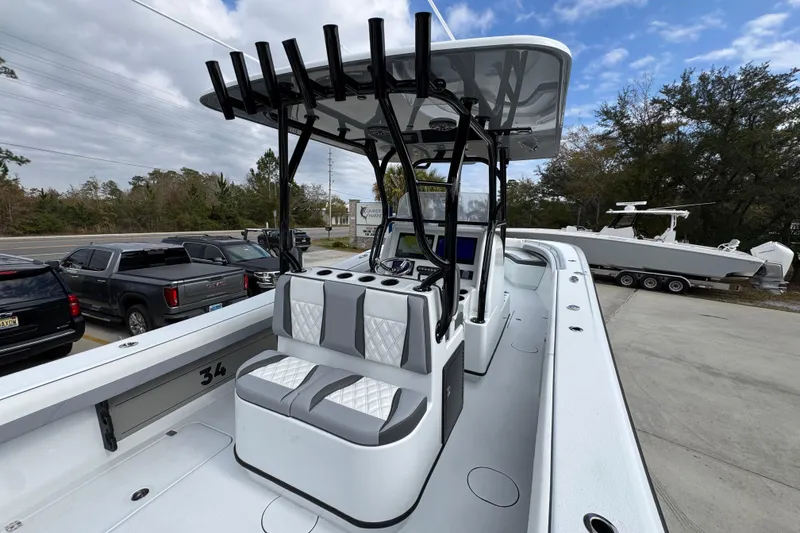 Slide: The Image of 2026 Yellowfin 34 Offshore boat interior with seating and rod holders, parked near vehicles. - 45