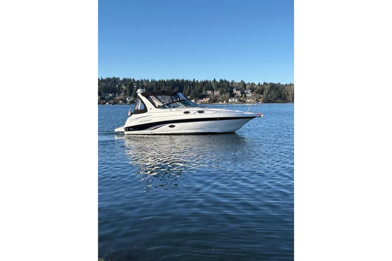 The Image of 2001 Chaparral Signature 300 boat cruising on a lake with forested shoreline. - 0