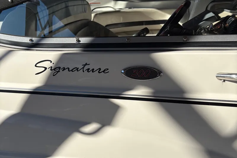Slide: The Image of Chaparral Signature 300 boat from 2001 on a serene lake with forested shoreline. - 1