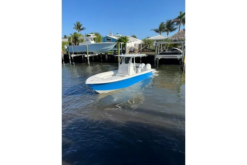 Slide: The Image of 2023 Contender 28 Tournament boat in blue, docked near waterfront homes. - 2