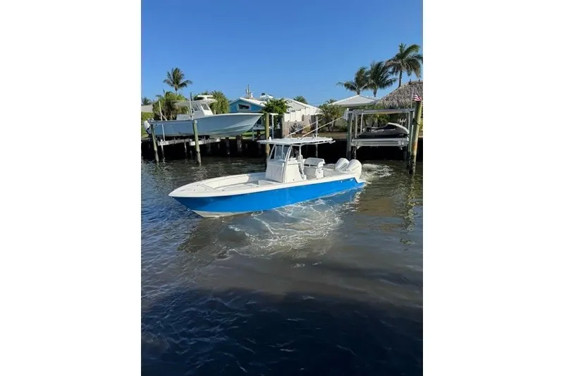 Slide: The Image of 2023 Contender 28 Tournament boat cruising on a sunny day near docks and palm trees. - 3