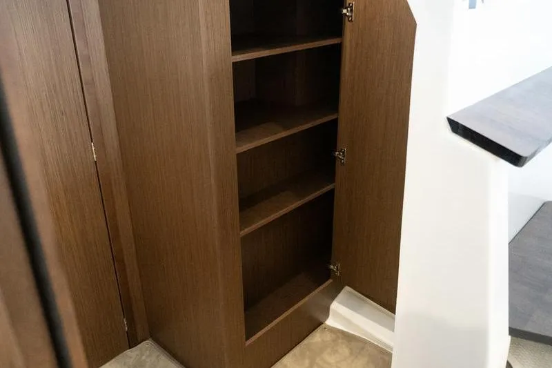 Slide: The Image of 2026 Beneteau Antares 11 Fly interior wooden storage cabinet with open shelves. - 26