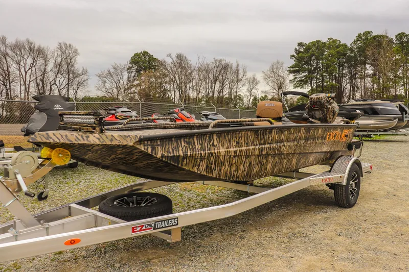 The Image of 2026 Excel 1751 Shallow Water F4 boat on trailer, camo design, parked outdoors. - 0