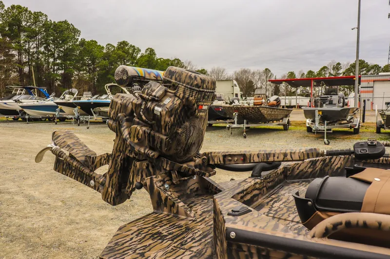 Slide: The Image of 2026 Excel 1751 Shallow Water F4 boat with camo design, parked among other boats. - 12