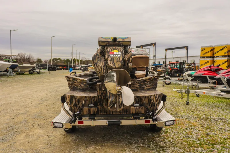 Slide: The Image of 2026 Excel 1751 Shallow Water F4 boat with camo design, parked in a dealership lot. - 3