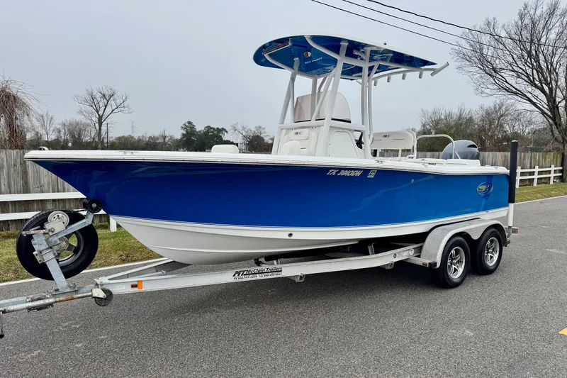 The Image of 2016 Sea Hunt Ultra 211 boat on trailer, blue hull, parked on roadside. - 1