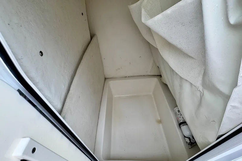 Slide: The Image of Interior storage compartment of 2016 Sea Hunt Ultra 211 boat, featuring white lining and a fire extinguisher. - 13