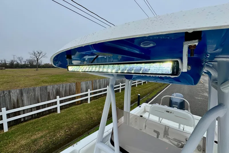 Slide: The Image of 2016 Sea Hunt Ultra 211 boat with LED light bar on T-top, parked near a fence. - 19