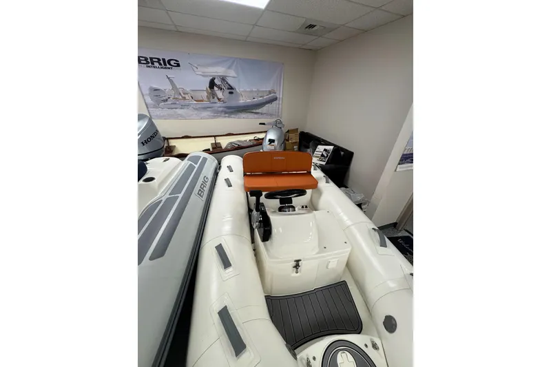 Slide: The Image of 2026 Brig Falcon 330 inflatable boat displayed indoors with seating and controls. - 4
