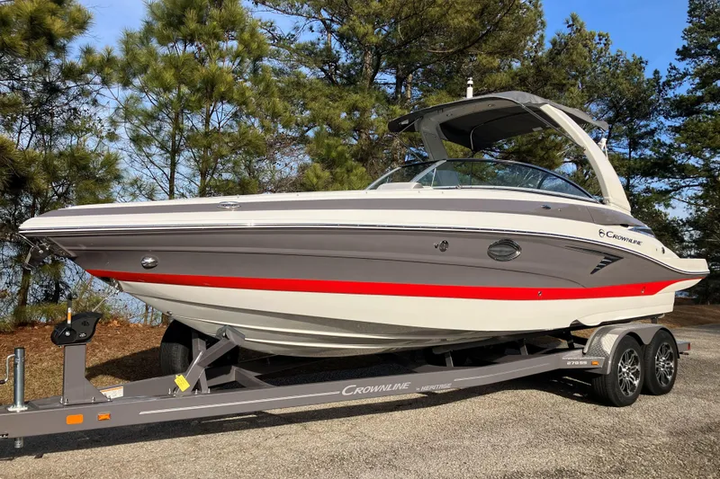 The Image of 2026 Crownline 220 SS boat on trailer, surrounded by trees, showcasing sleek design. - 1