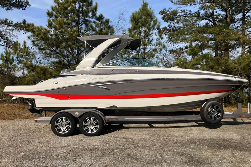 Slide: The Image of 2026 Crownline 220 SS boat on trailer, parked outdoors with trees in background. - 3