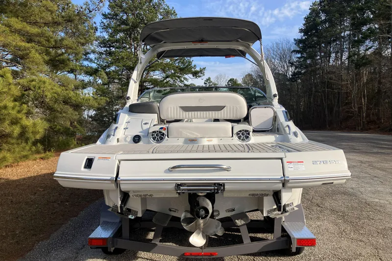 Slide: The Image of 2026 Crownline 220 SS boat, rear view, parked on a forested road. - 5