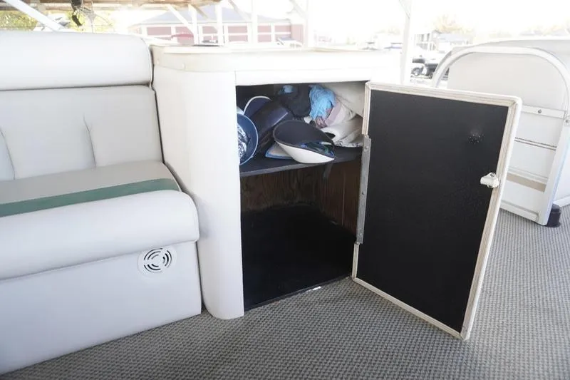 Slide: The Image of Open storage compartment on 2000 Sundancer Pontoons 240 Majestic boat with various items inside. - 23