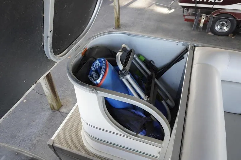 Slide: The Image of Open storage compartment on 2000 Sundancer Pontoons 240 Majestic, containing beach chairs and accessories. - 31