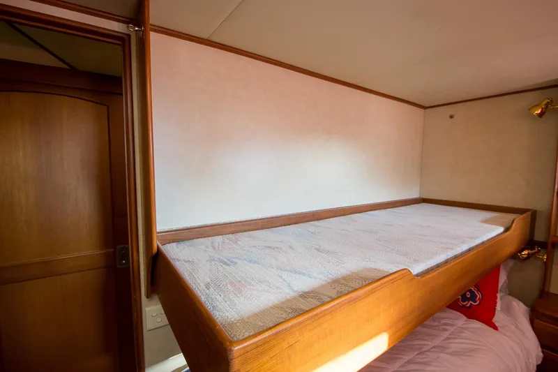 Slide: The Image of Upper bunk bed in 2000 Fleming 55 yacht cabin, featuring wooden frame and cozy bedding. - 14