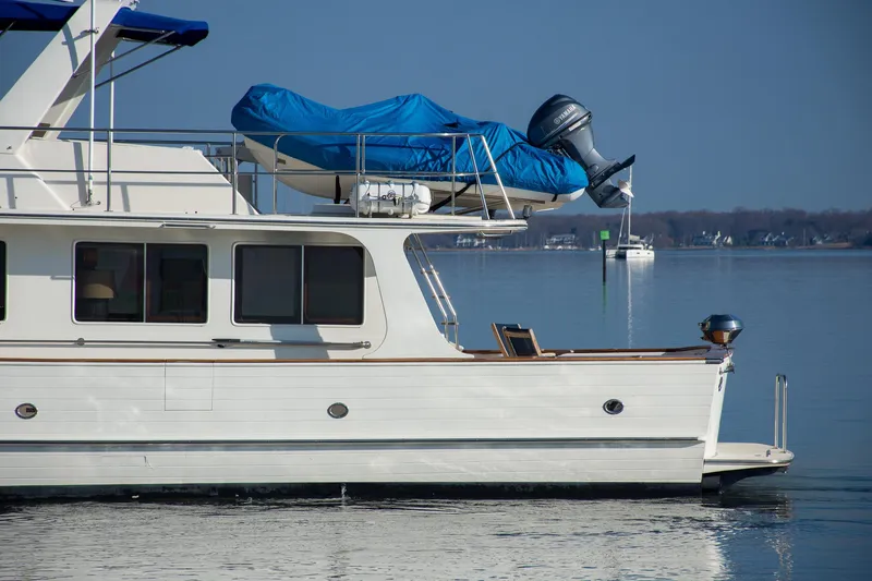 Slide: The Image of Side view of a 2000 Fleming 55 yacht on calm water, featuring a covered dinghy. - 39