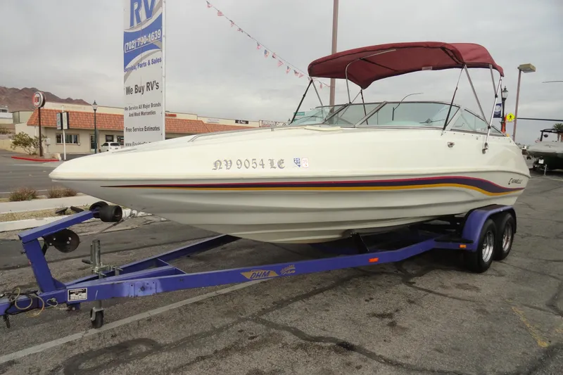 Slide: The Image of 1997 Caravelle Interceptor 232 boat on trailer, parked in a lot with RV dealership sign. - 2