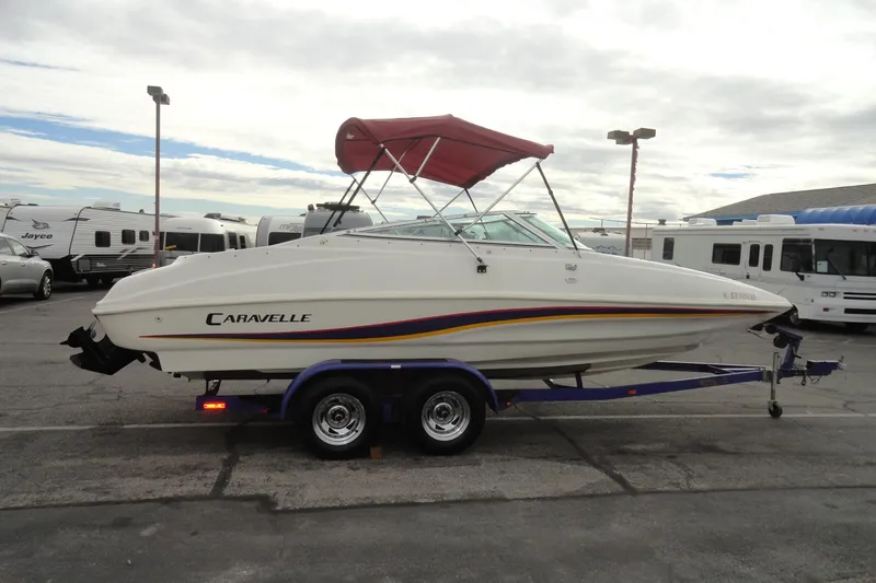 Slide: The Image of 1997 Caravelle Interceptor 232 boat with red canopy on trailer in parking lot. - 5