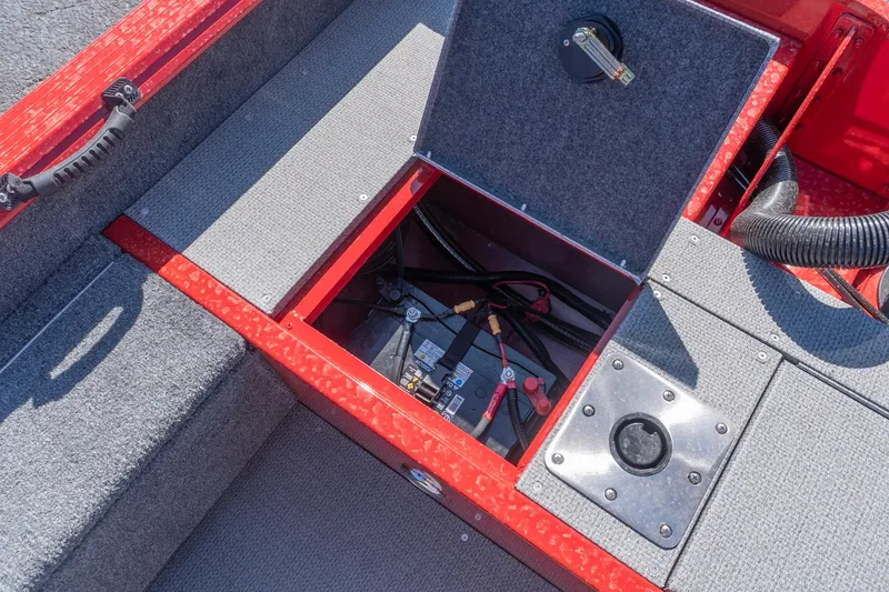 Slide: The Image of 2026 G3 Angler V21 F boat battery compartment with red trim and gray carpet. - 15