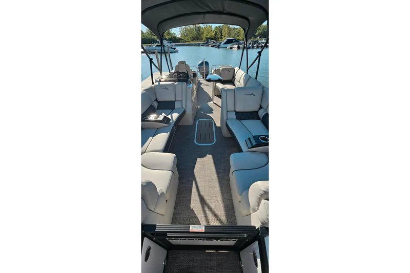 Slide: The Image of 2018 Bennington 25 QCW pontoon boat interior with spacious seating and canopy on a sunny day. - 12