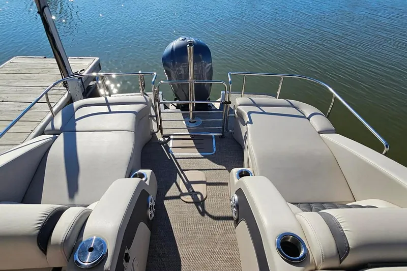 Slide: The Image of 2018 Bennington 25 QCW pontoon boat with plush seating, docked by the water. - 14