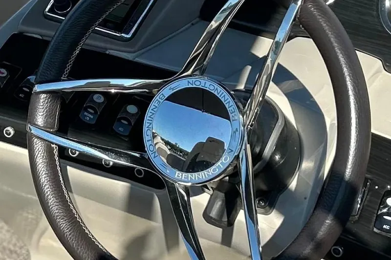 Slide: The Image of Steering wheel of a 2018 Bennington 25 QCW boat, featuring chrome and leather design. - 21