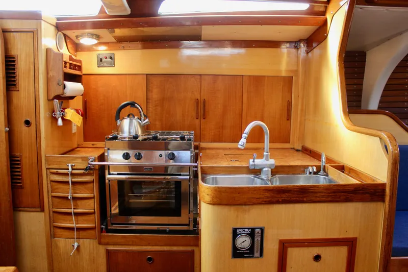 Slide: The Image of Interior of 1973 Nautor Swan 44 yacht kitchen with stove, sink, and wooden cabinetry. - 35