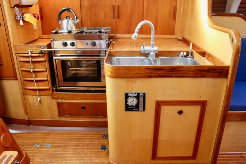 Slide: The Image of 1973 Nautor Swan 44 yacht kitchen with stove, sink, and wooden cabinetry. - 36