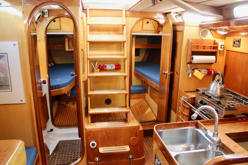 Slide: The Image of Interior of a 1973 Nautor Swan 44 sailboat, featuring wooden cabinetry and a compact kitchen. - 51