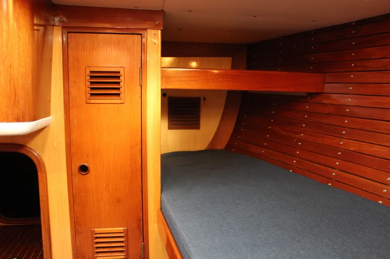 Slide: The Image of Interior of 1973 Nautor Swan 44 yacht with wooden paneling and blue cushioned berth. - 56