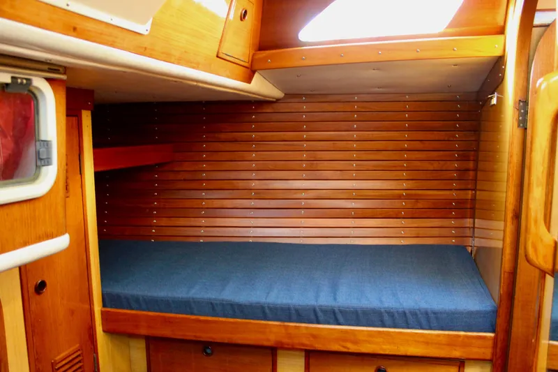 Slide: The Image of Cozy cabin interior of 1973 Nautor Swan 44 sailboat with wooden paneling and blue bedding. - 57
