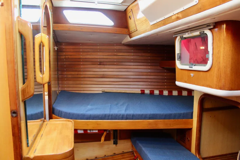 Slide: The Image of Cozy cabin interior of 1973 Nautor Swan 44 sailboat with wooden paneling and blue cushions. - 58