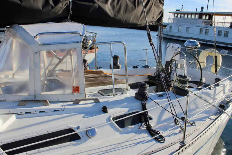 Slide: The Image of 1973 Nautor Swan 44 sailboat deck with winches and cockpit, docked by the water. - 6