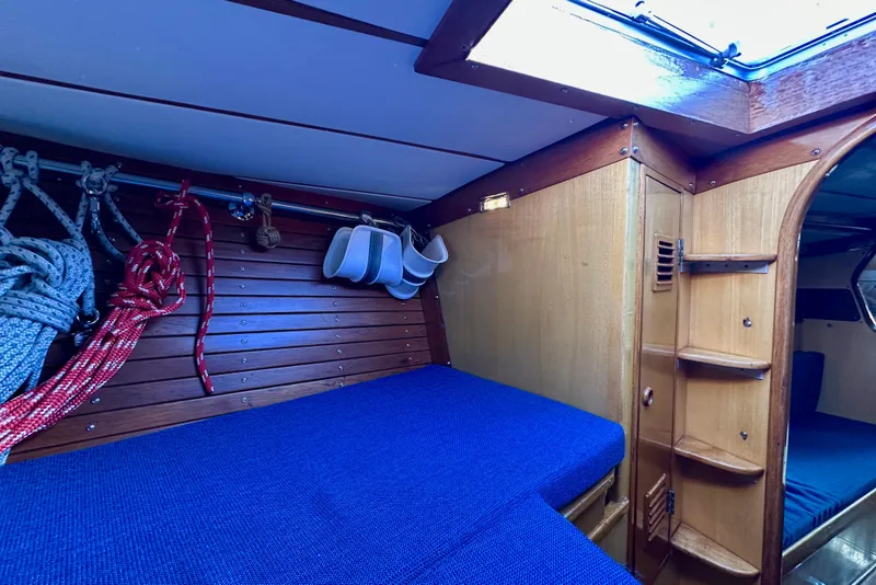 Slide: The Image of Interior of 1973 Nautor Swan 44 sailboat with blue bedding and wooden paneling. - 78