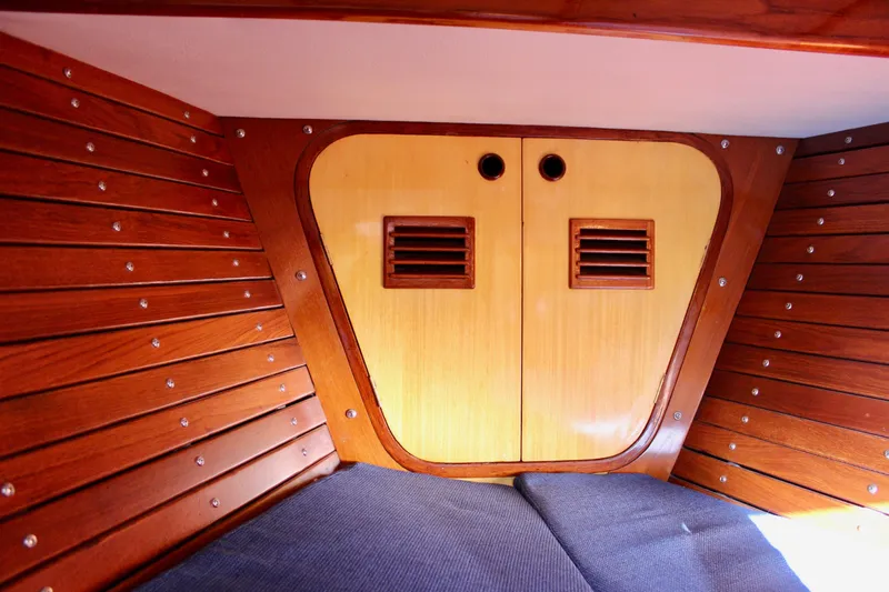 Slide: The Image of Interior of 1973 Nautor Swan 44 sailboat with wooden paneling and storage compartment. - 83