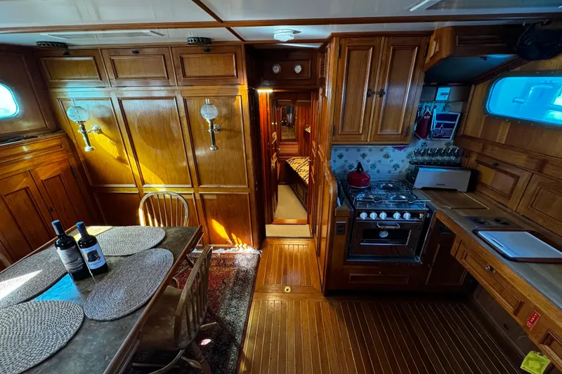 Slide: The Image of Interior of a 1974 Doggersbank 63 yacht with wooden cabinetry and dining area. - 16