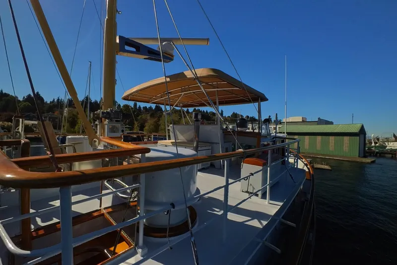 Slide: The Image of 1974 Doggersbank 63 yacht docked, featuring wooden railings and canopy under clear blue sky. - 21