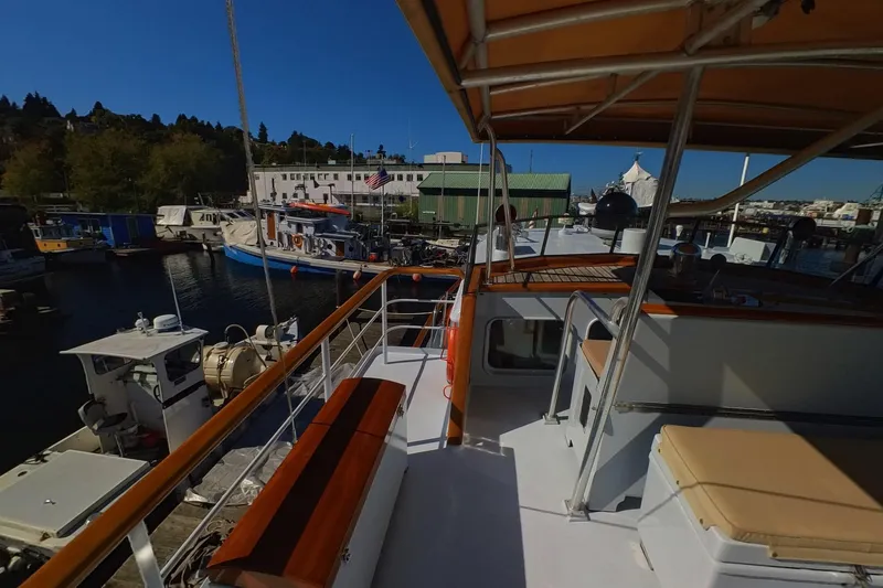 Slide: The Image of 1974 Doggersbank 63 yacht docked at a marina, featuring a spacious deck and seating area. - 22