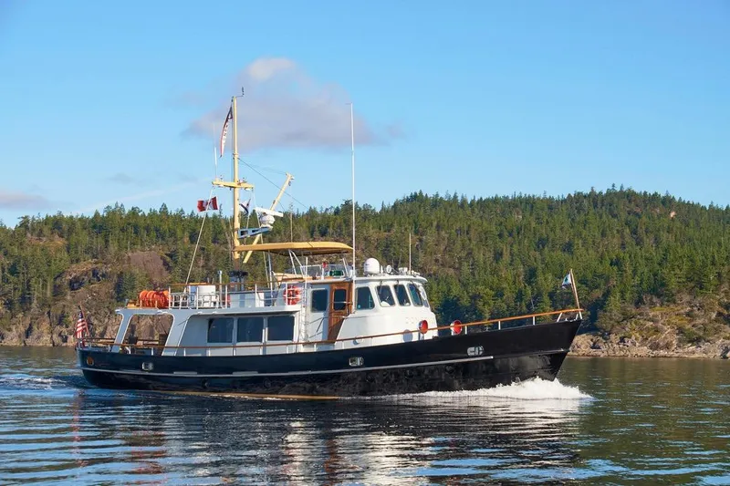 Slide: The Image of 1974 Doggersbank 63 yacht cruising on a serene lake with forested hills. - 43