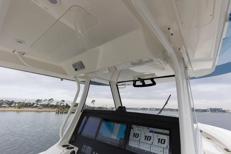 Slide: The Image of 2024 Regulator 37 boat helm with advanced navigation displays on a calm water backdrop. - 21