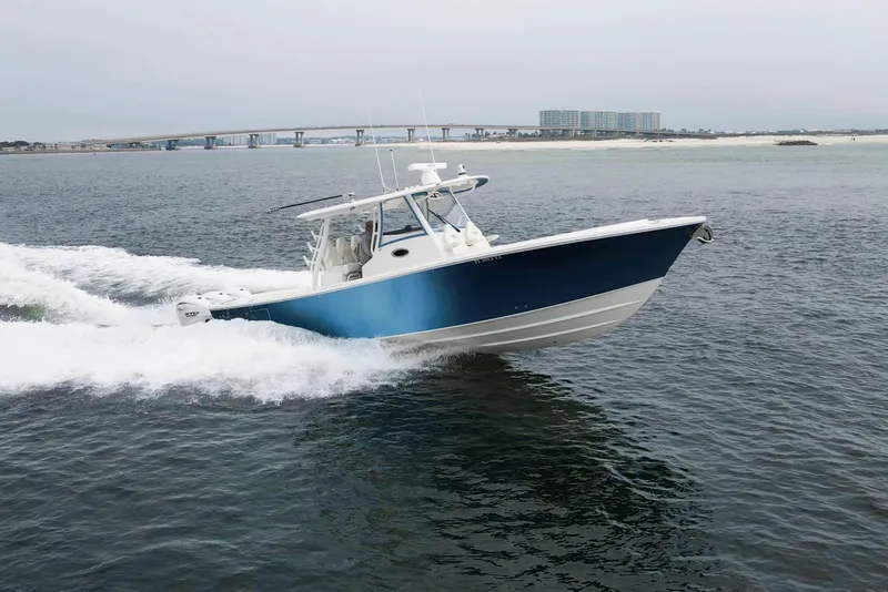 Slide: The Image of 2024 Regulator 37 boat cruising on open water near a coastal bridge. - 37