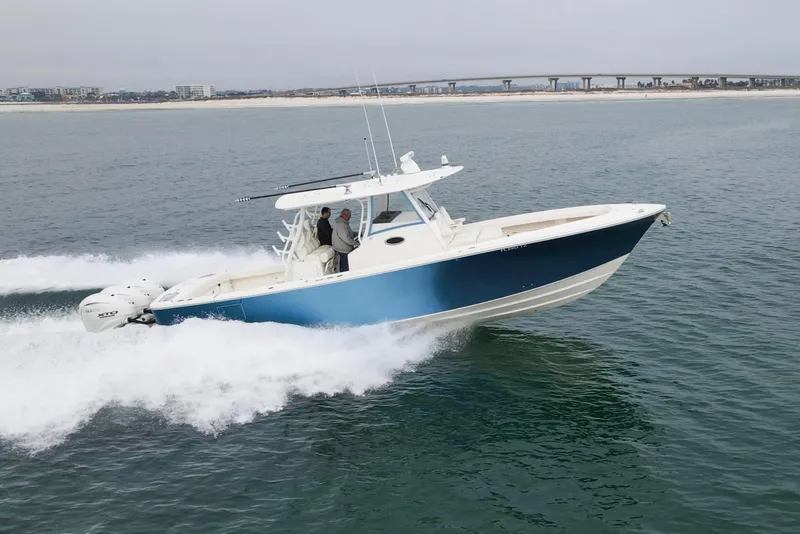 Slide: The Image of 2024 Regulator 37 boat cruising on open water with cityscape in background. - 38