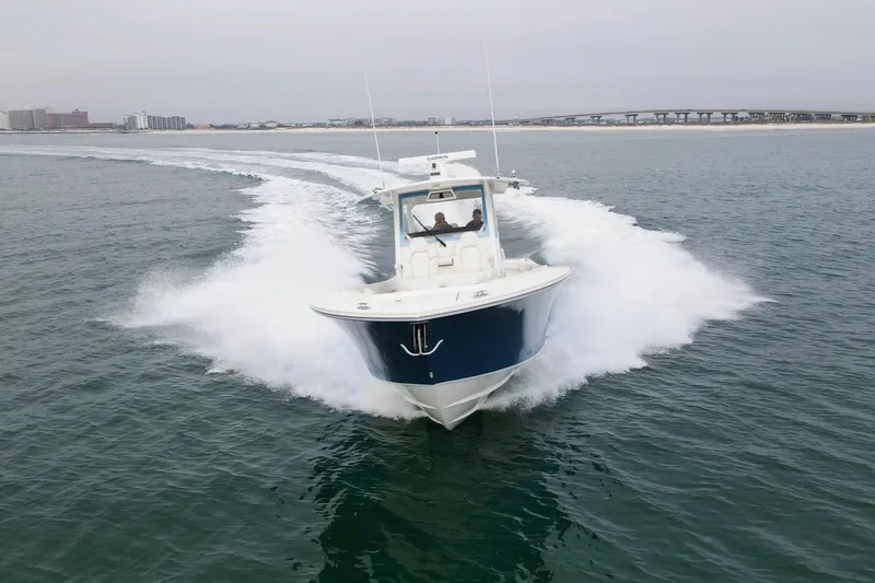 Slide: The Image of 2024 Regulator 37 boat cruising on open water with cityscape in background. - 39