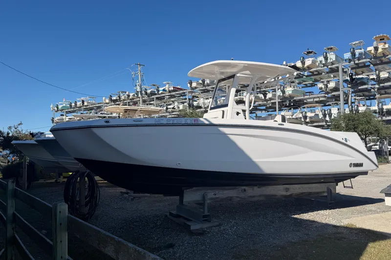 The Image of 2022 Yamaha Boats 252 FSH Sport in storage, side view under clear blue sky. - 1