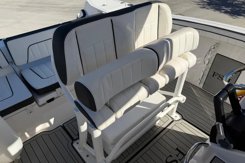 Slide: The Image of 2022 Yamaha Boats 252 FSH Sport interior seating with white upholstery and helm details. - 19