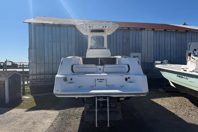 Slide: The Image of 2022 Yamaha Boats 252 FSH Sport, rear view, docked beside a metal building. - 3