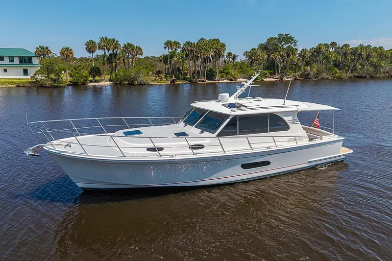 The Image of 2024 Grand Banks 44 Eastbay yacht cruising on a serene river with lush greenery. - 0
