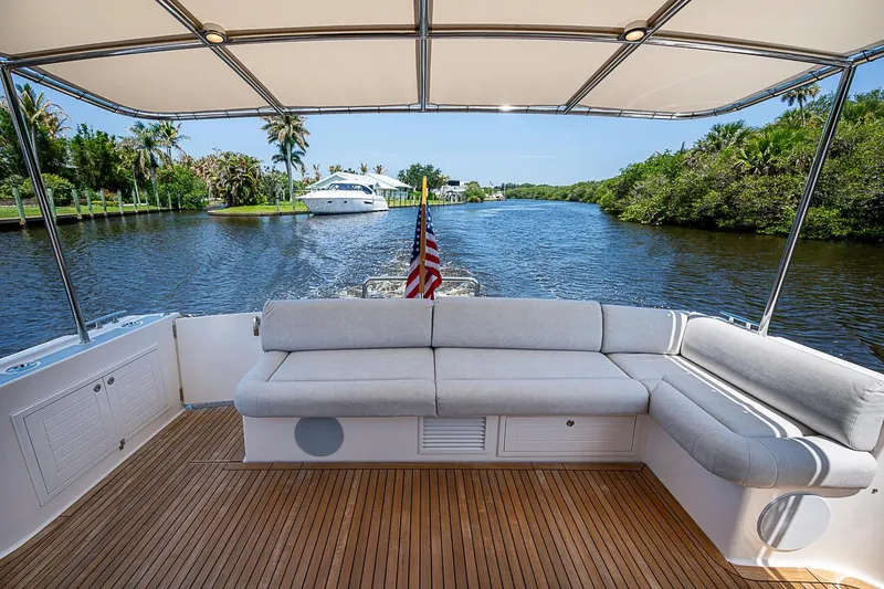 Slide: The Image of 2024 Grand Banks 44 Eastbay yacht deck with seating, cruising on a scenic waterway. - 12